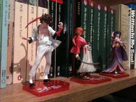 Left to right: Sanosuke Sagara, Kenshin Himura, Kaoru Kamiya and the book by Joseph Conrad I “borrowed” the phrase “dark, but glowingly alive” from. It’s the one standing on the left to “Written In My Soul”. What, did you think I was making that delectable part of the review up? Tsk.